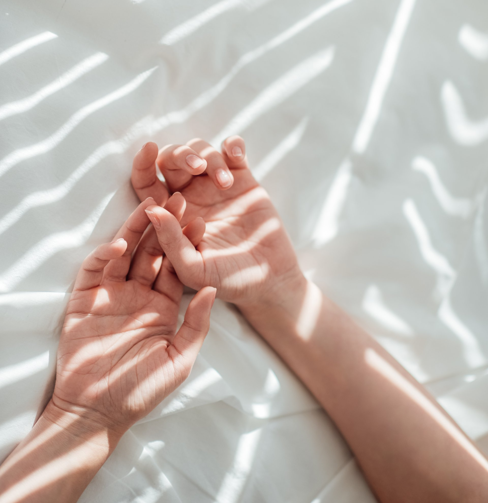 a woman with good hands stretched out on white sheets