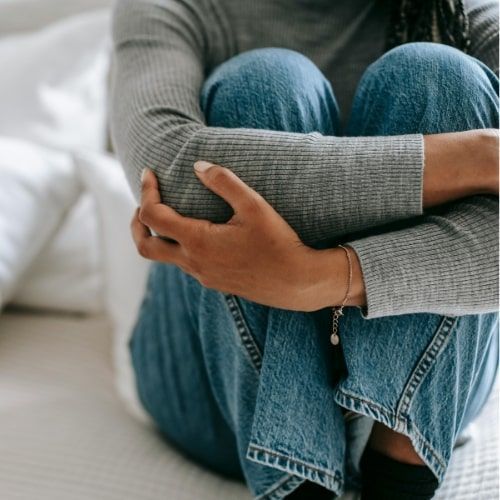A woman is sitting on the floor with her legs crossed.