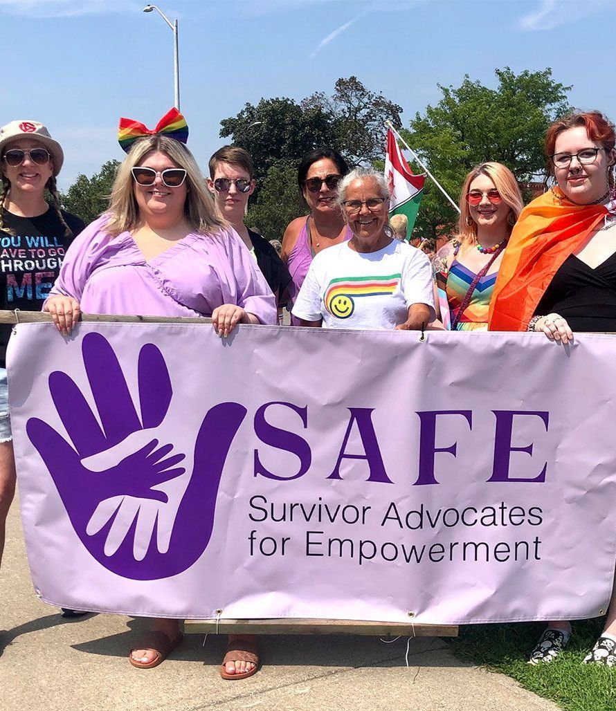 a group of women holding a safe survivor advocates for empowerment banner