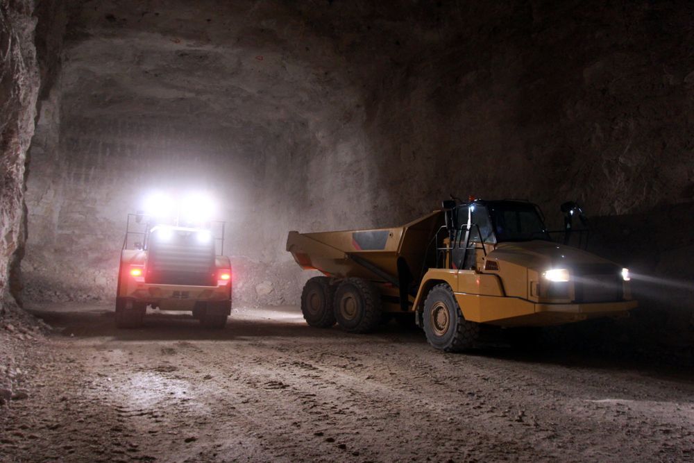 Two Trucks Are Driving Down a Dirt Road in A Tunnel — PBC Compliancing in Moranbah, QLD