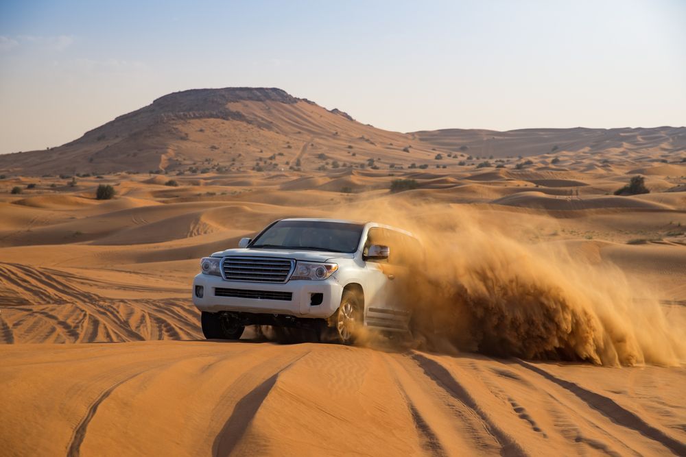 A White Suv Is Driving Through the Sand in The Desert — PBC Compliancing in Dysart, QLD