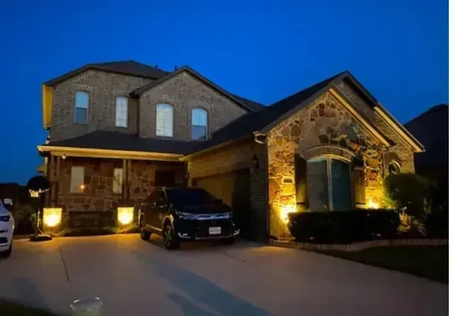 Local Electricians – A beautifully lit residential home showcases expert outdoor lighting installed by skilled local electricians. The warm accent lighting highlights the home’s stone and brick exterior, enhancing its curb appeal during the evening hours.