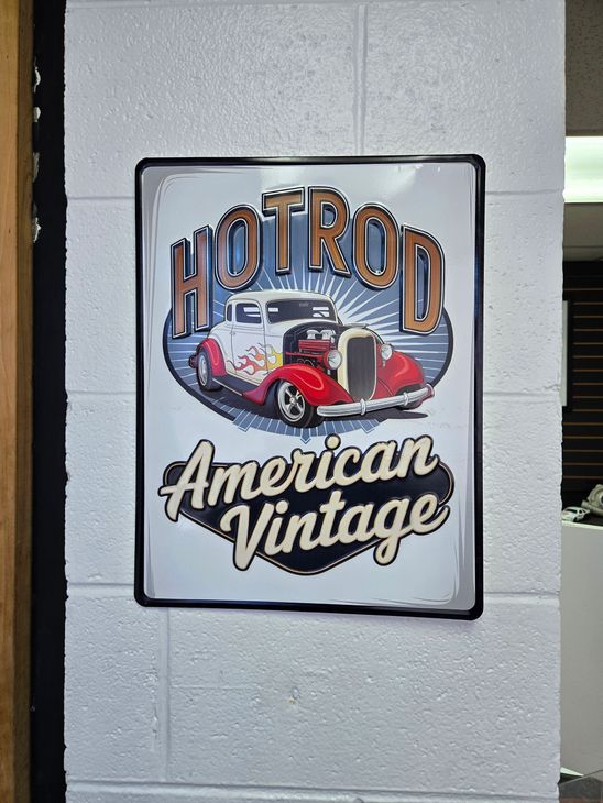 Hot Rod American Vintage sign with a red classic car on a gray cinderblock wall