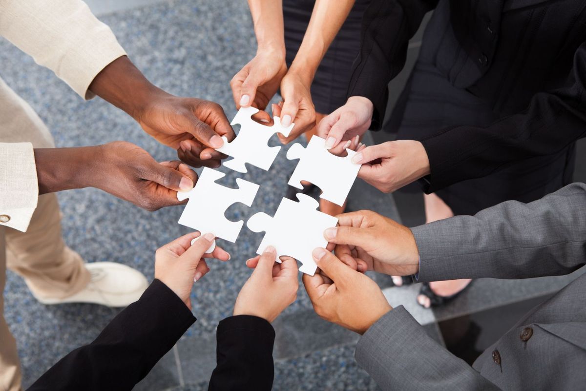 A group of people are putting puzzle pieces together in a circle