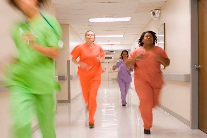 A group of nurses are running down a hospital hallway