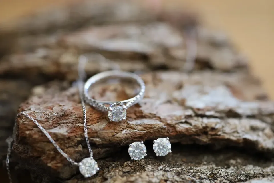 Diamond jewelry set on rough stone, including a ring, necklace, and earrings
