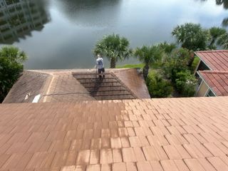 Technician soft-washing a tile roof to safely clear black algae streaks and dirt