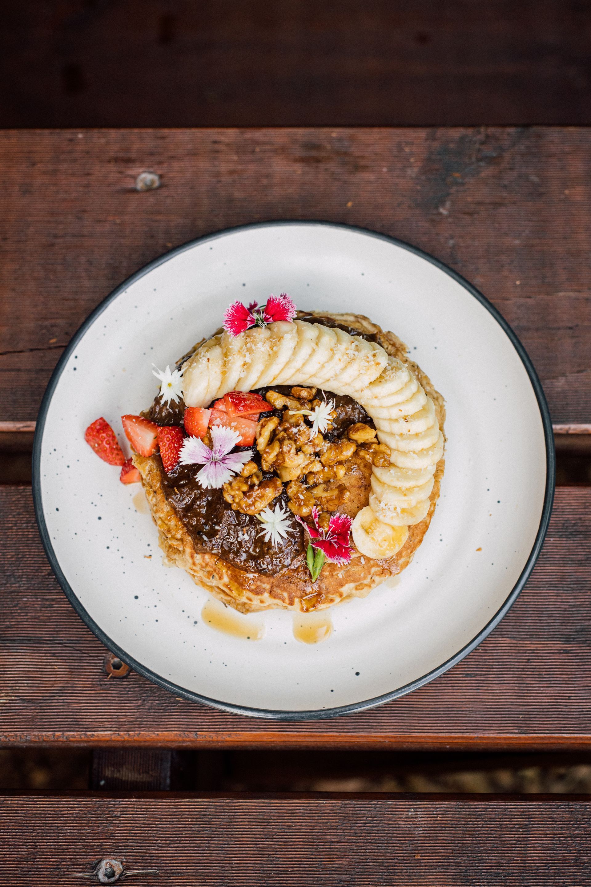 A plate of food with bananas and strawberries on a wooden table.