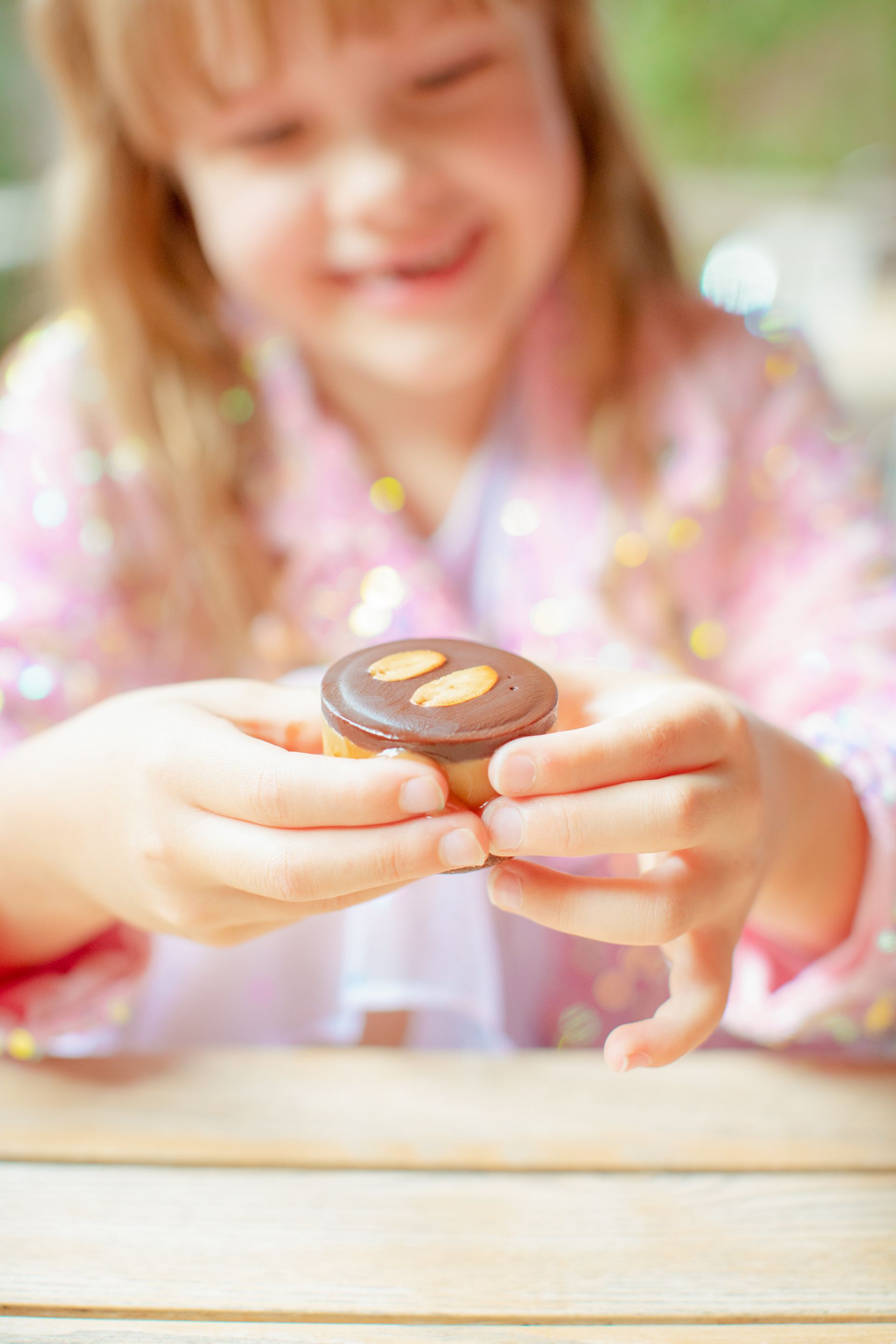 A little girl is holding a chocolate cupcake in her hands.