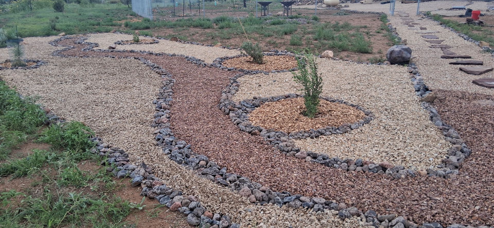 Decorative stone garden path with a small plant in the center, bordered by grass and gravel