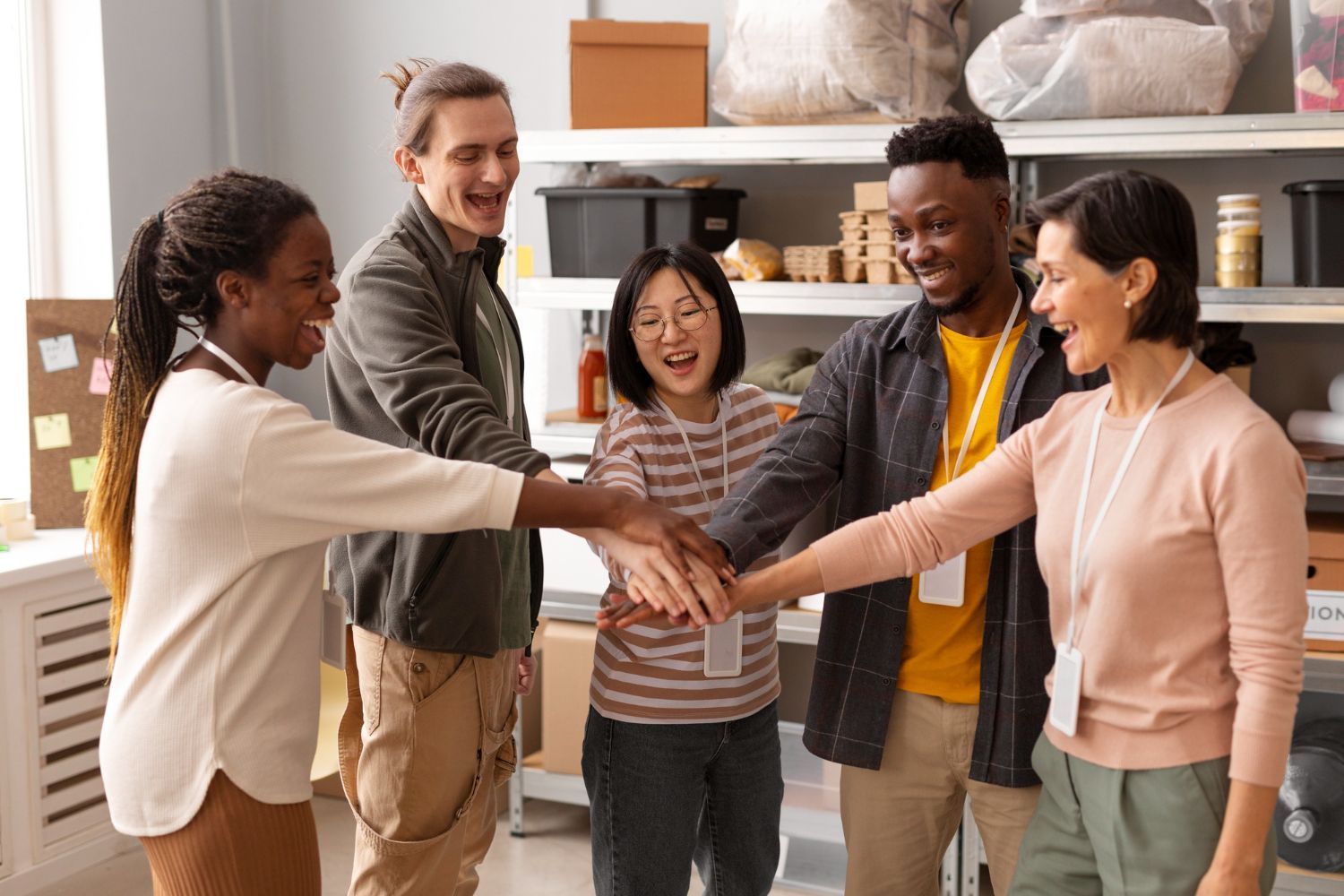 A group of people are putting their hands together in a room.