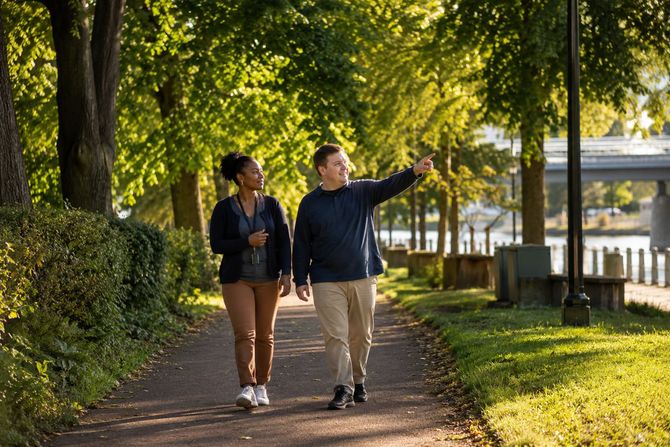 Direct support professional walking with an adult in a community park