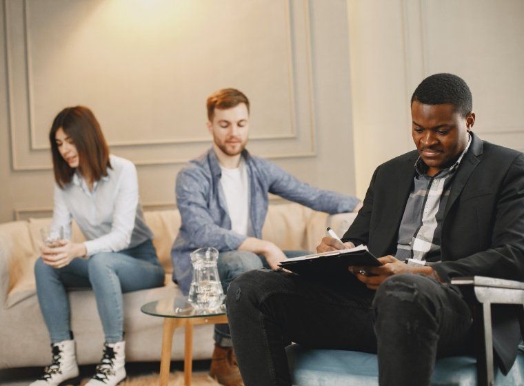 A man in a suit is sitting in a waiting room with two other people.