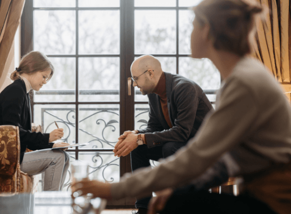 A group of people are sitting in a living room talking to each other.