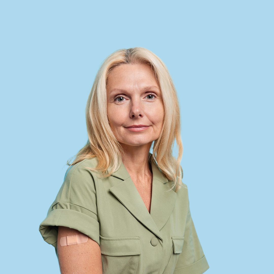A woman in a green shirt has a bandage on her arm.