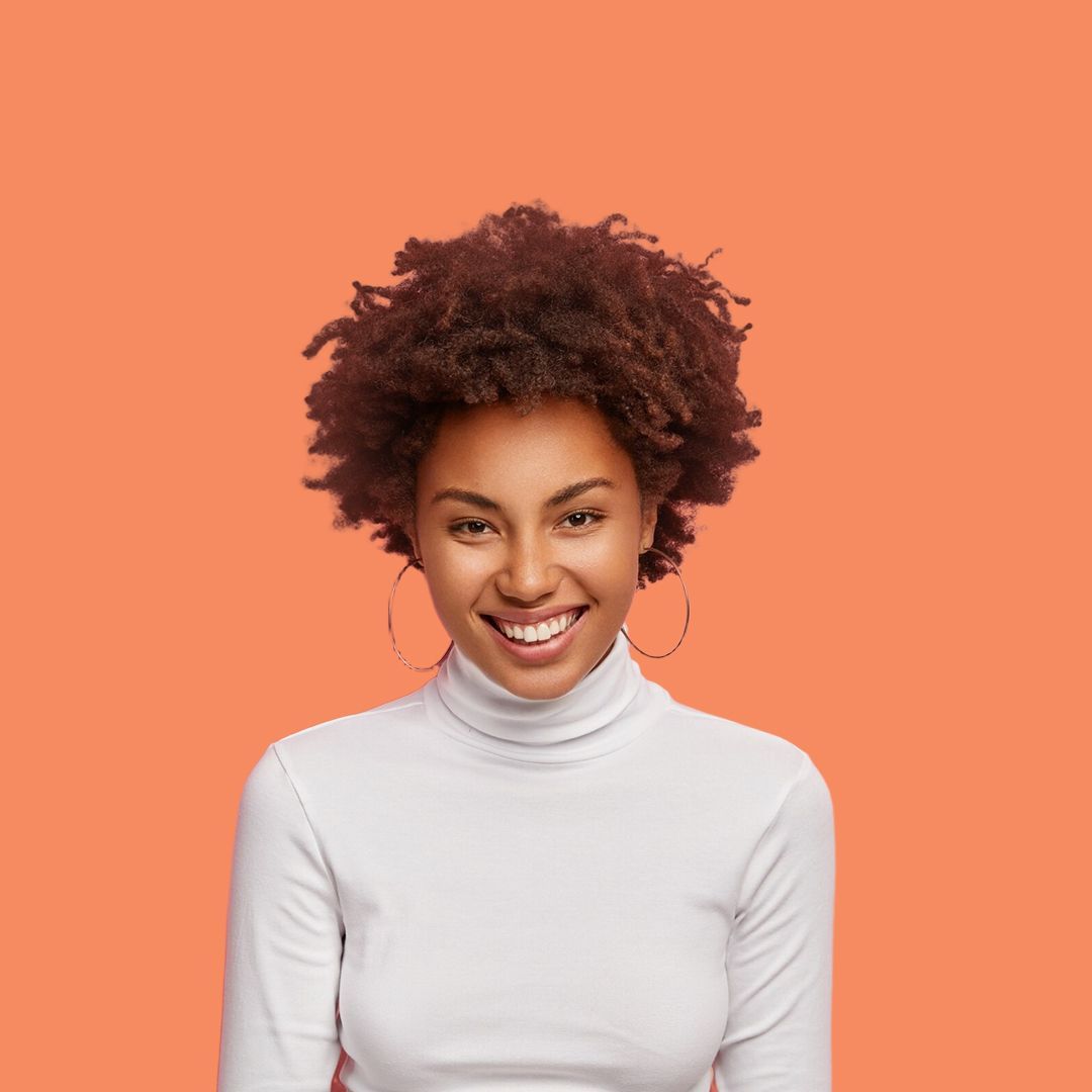 A woman with curly hair is wearing a white turtleneck and smiling.