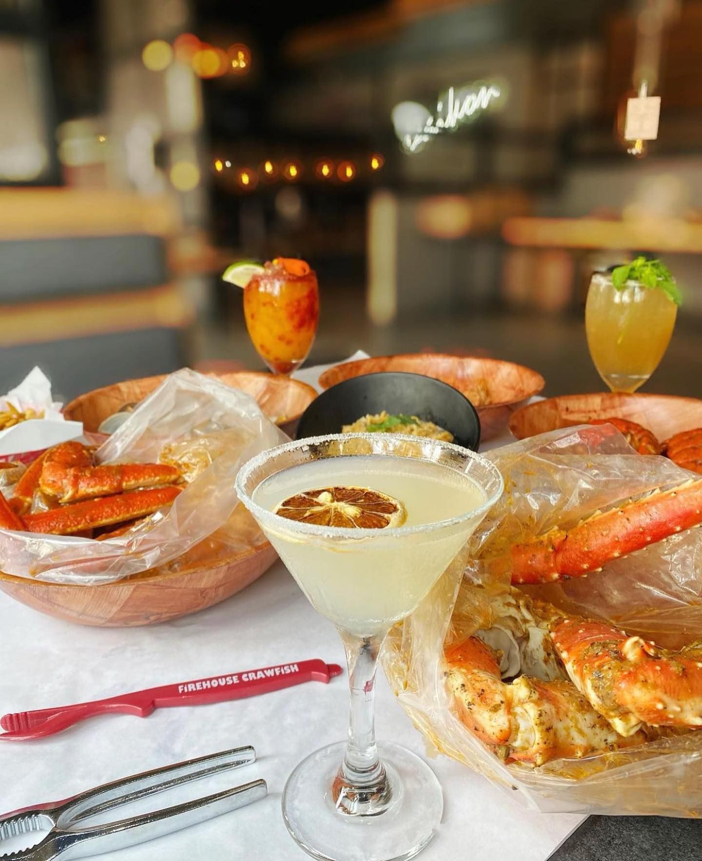 Seafood platter and two cocktails on a restaurant table with a blurred bar in the background