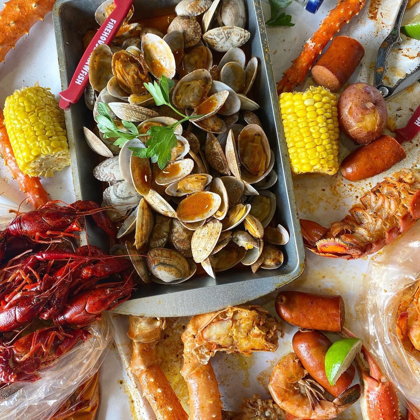 Seafood boil with clams, crab, shrimp, corn, and sausage on a tray lined with paper.