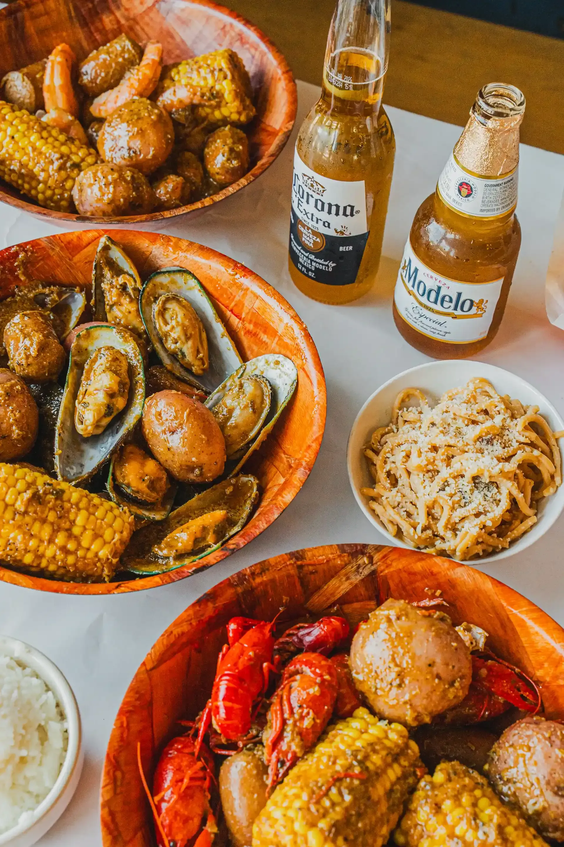 Assorted tapas and seafood dishes with two bottles of beer on a table