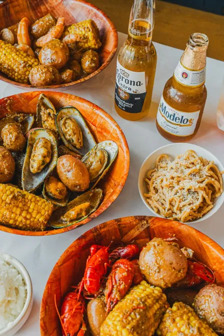 Bowls of grilled seafood and fried snacks with two beer bottles on a table