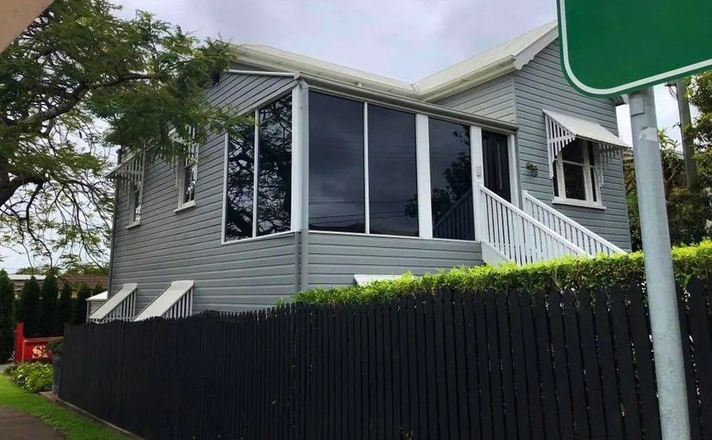 A House with A Black Fence and A Green Sign in Front of It — Solarmaster in Brisbane, QLD