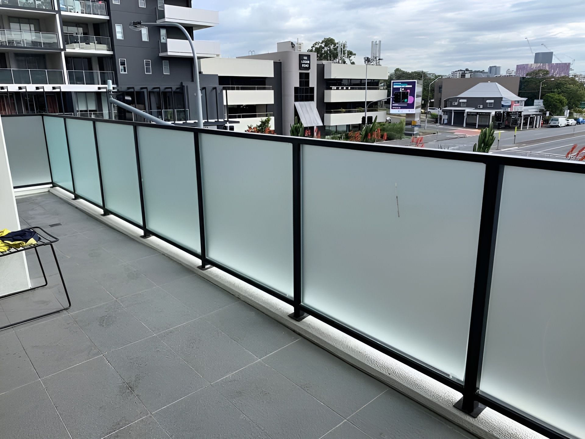 Balcony with frosted windows Brisbane overlooking a city street and surrounding buildings.