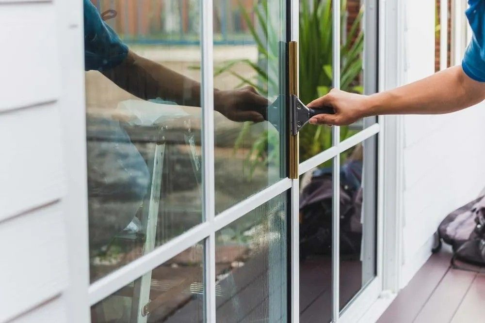 A Man Is Opening a Sliding Glass Door with A Key — Solarmaster in Murarrie, QLD