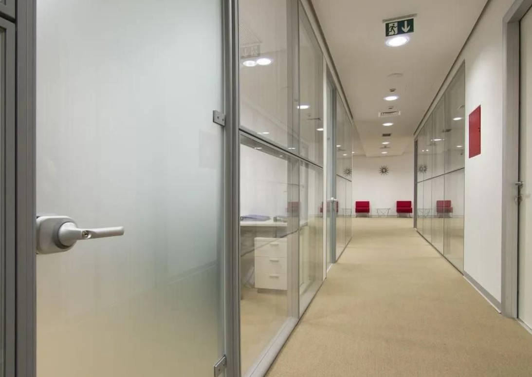 Modern commercial office corridor with floor-to-ceiling glass partitions featuring frosted film.
