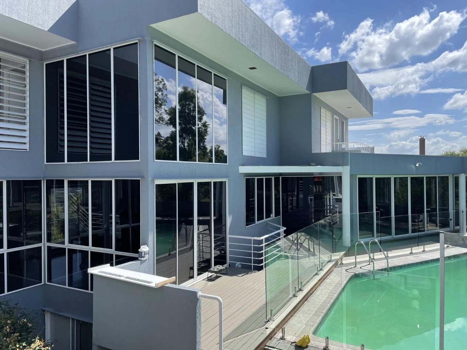 A Large House with A Swimming Pool in Front of It — Solarmaster in Gold Coast, QLD