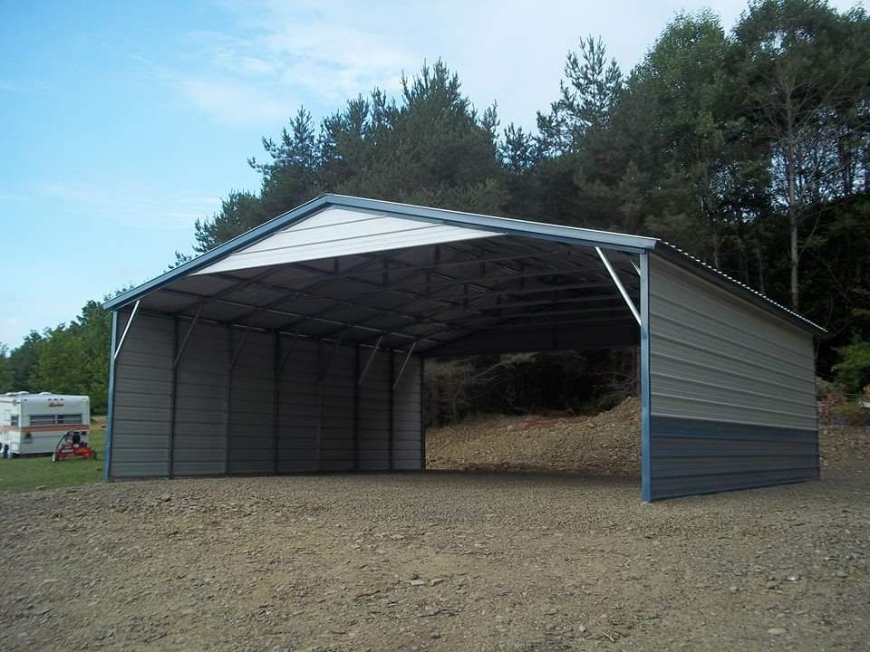 Gray and blue metal carport on a gravel surface with trees in the background.