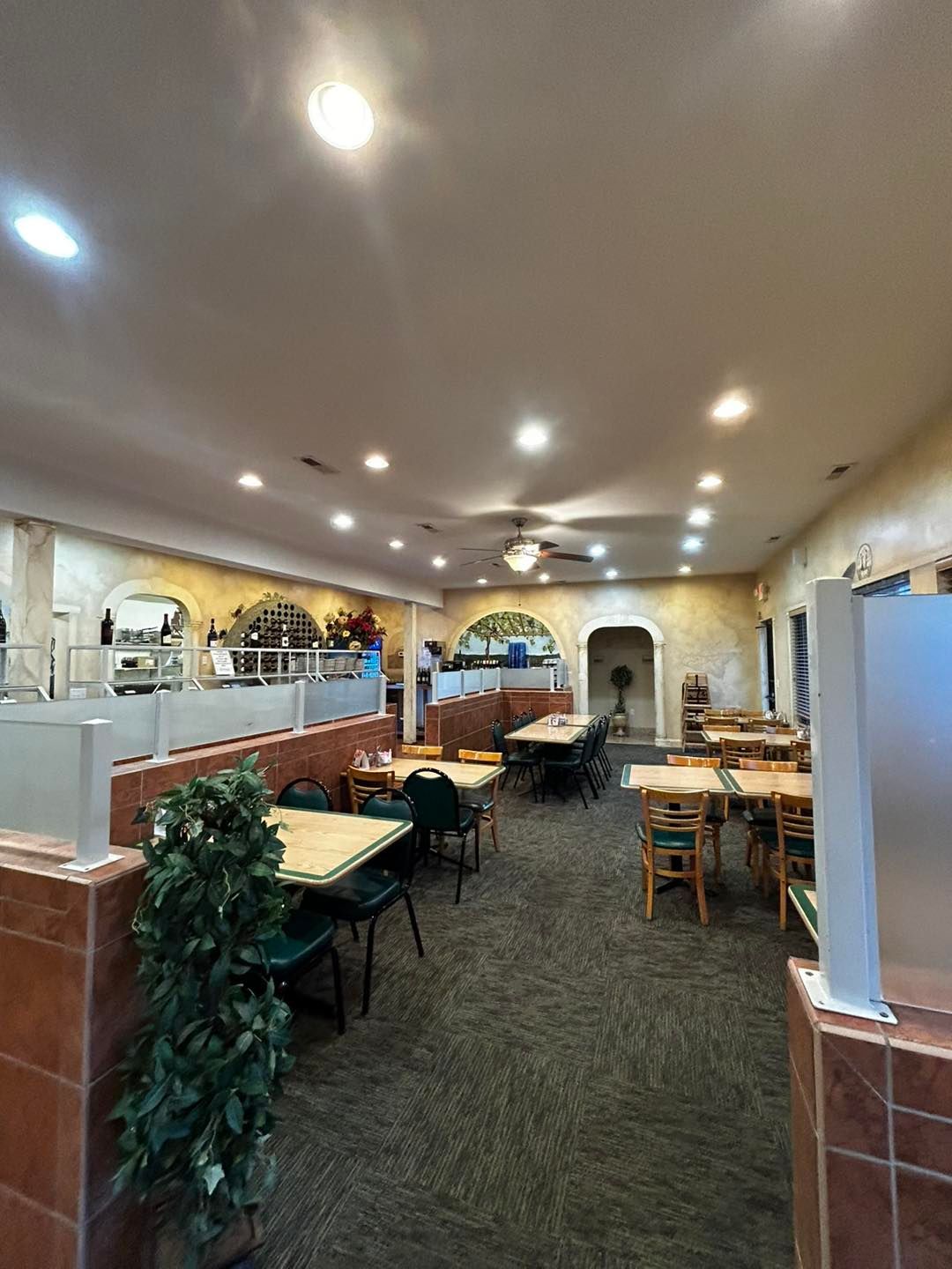 Restaurant interior with tables and chairs, decorative arches, and ceiling lights.