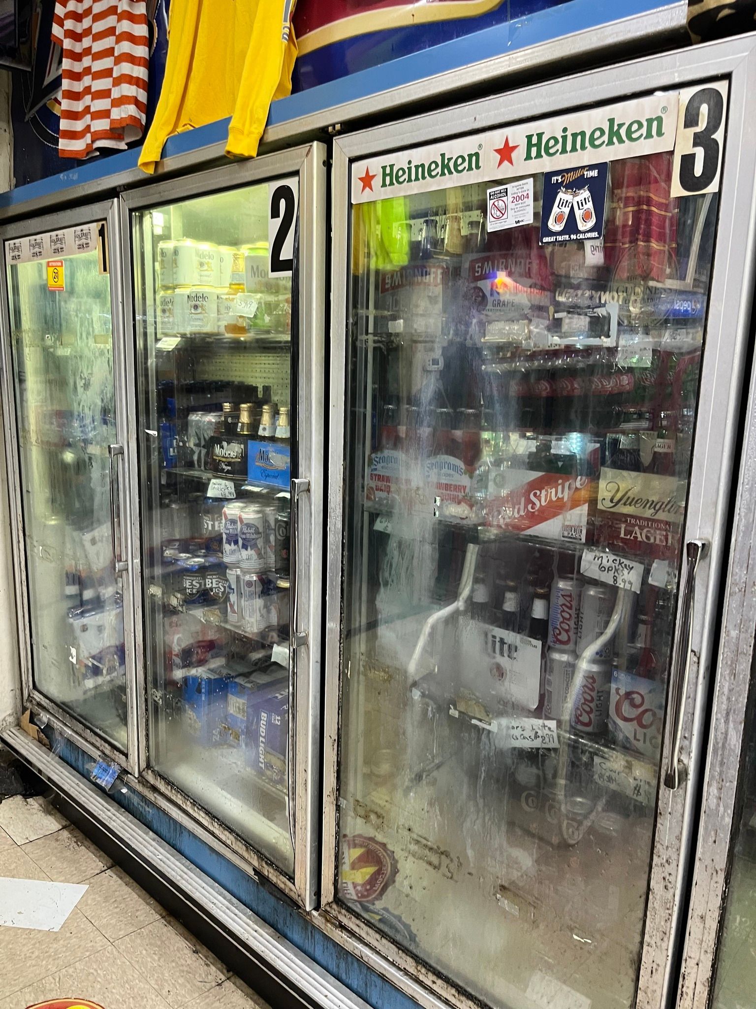 Cooler with glass doors, stocked with beverages and labeled 