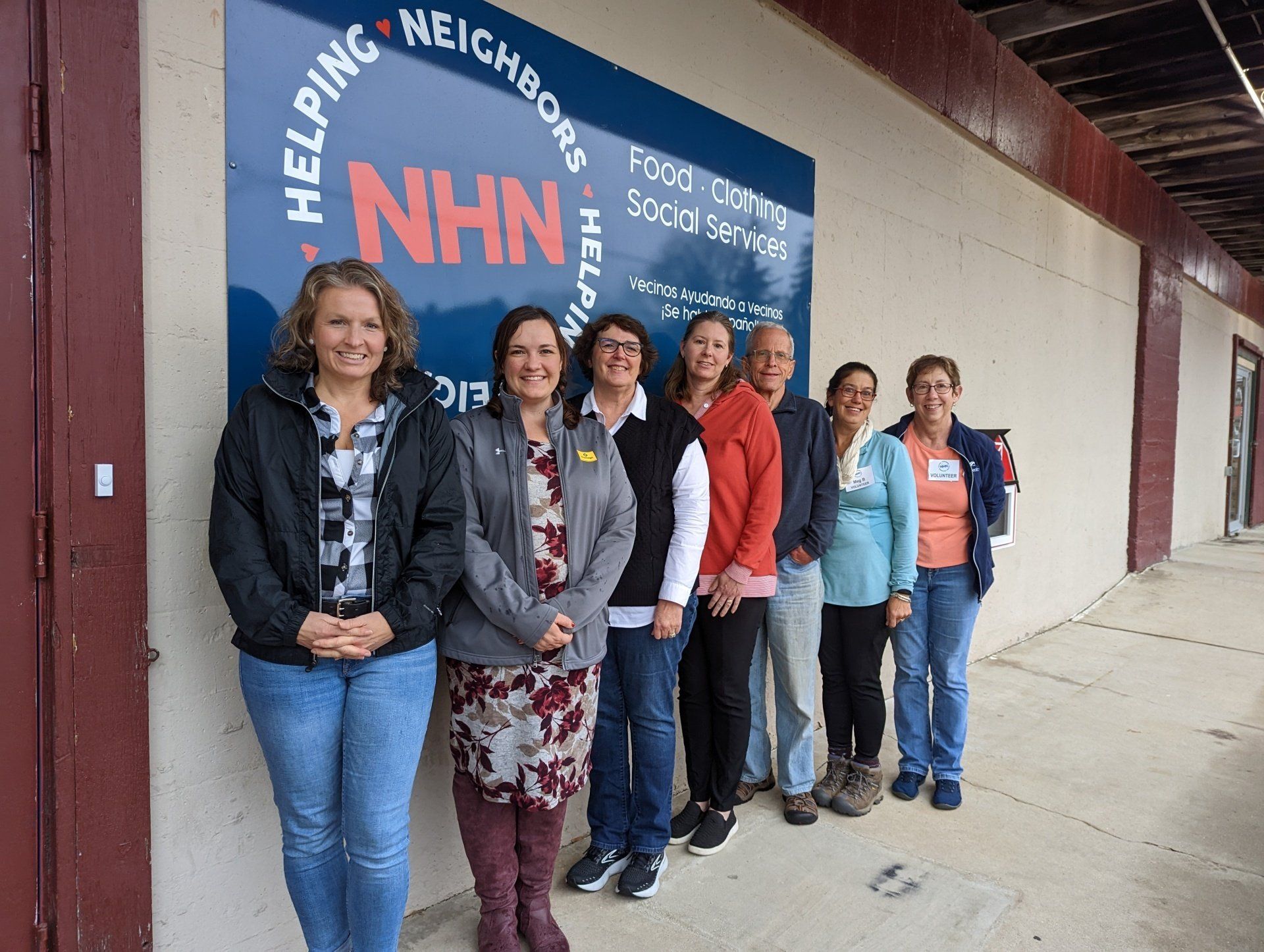 Group of seven people standing in front of a blue NHN sign; building exterior.
