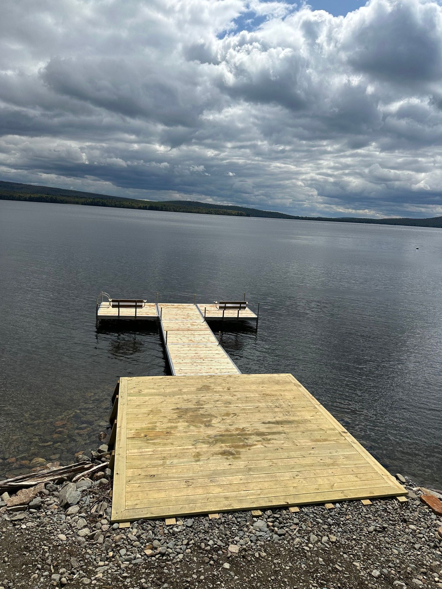 Wooden dock extending into a calm lake under a cloudy sky