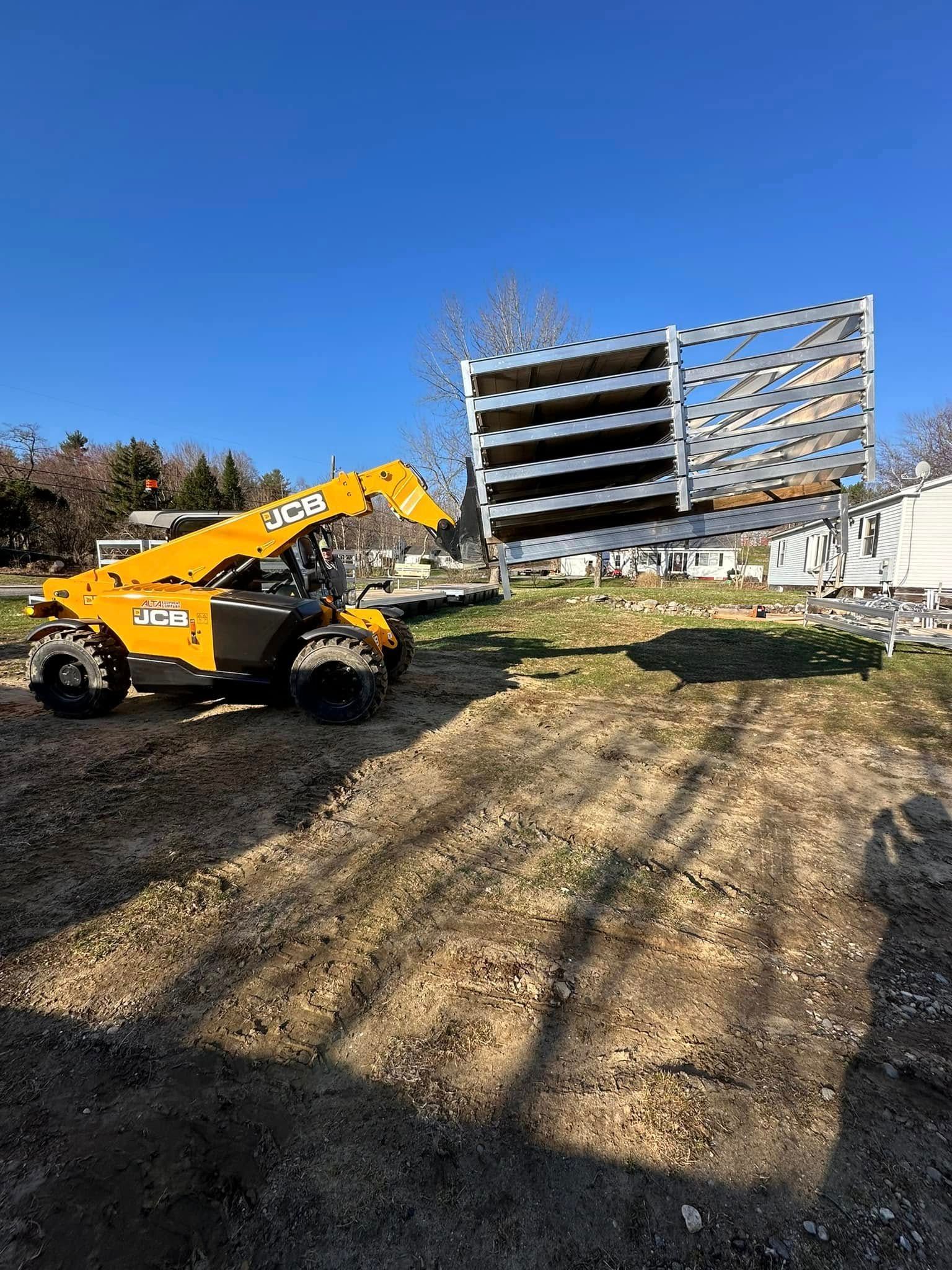 Yellow construction loader in a dirt lot near a partially built concrete apartment building under a clear blue sky.