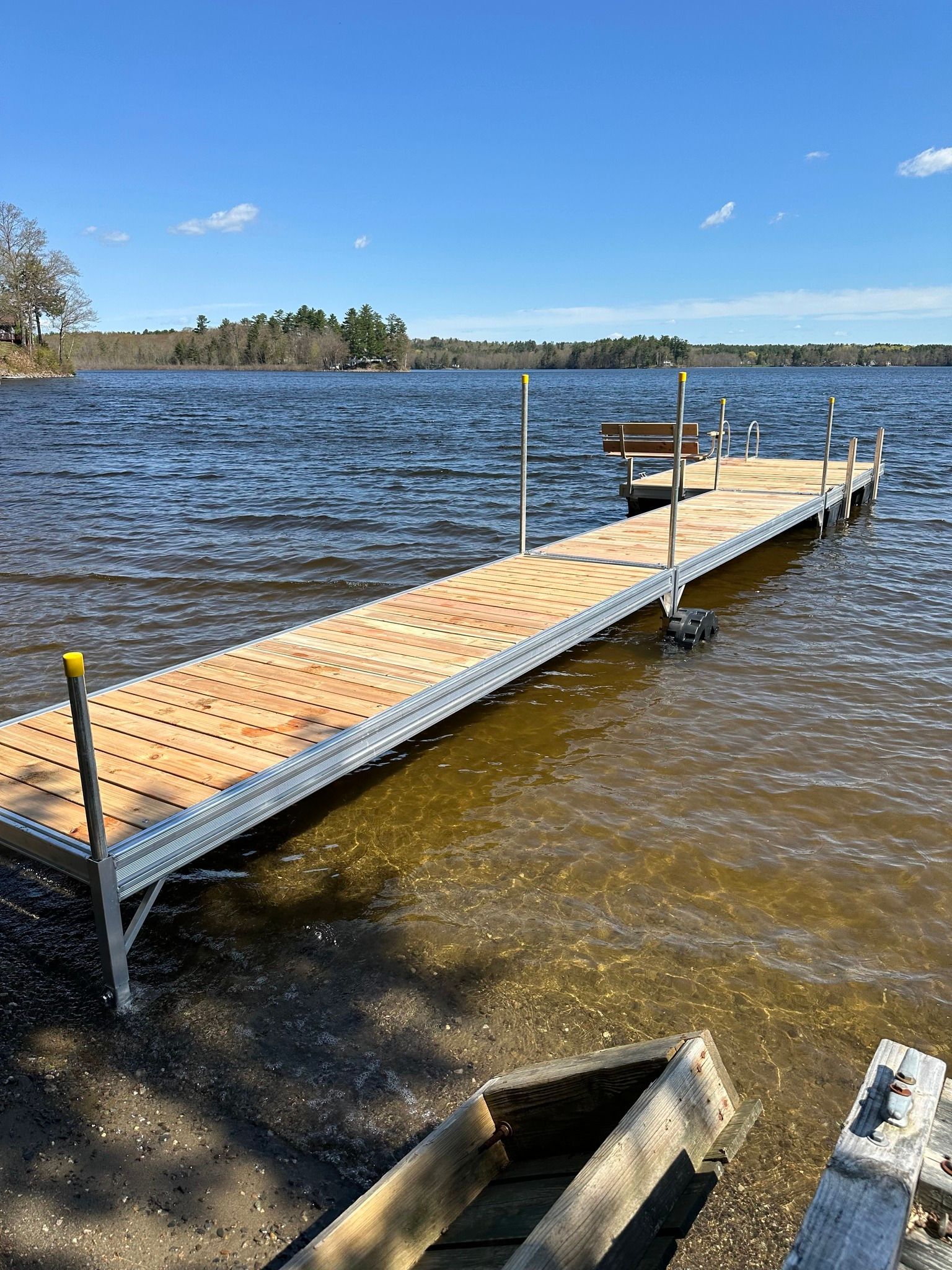 Wooden dock extending into a choppy lake under a clear blue sky