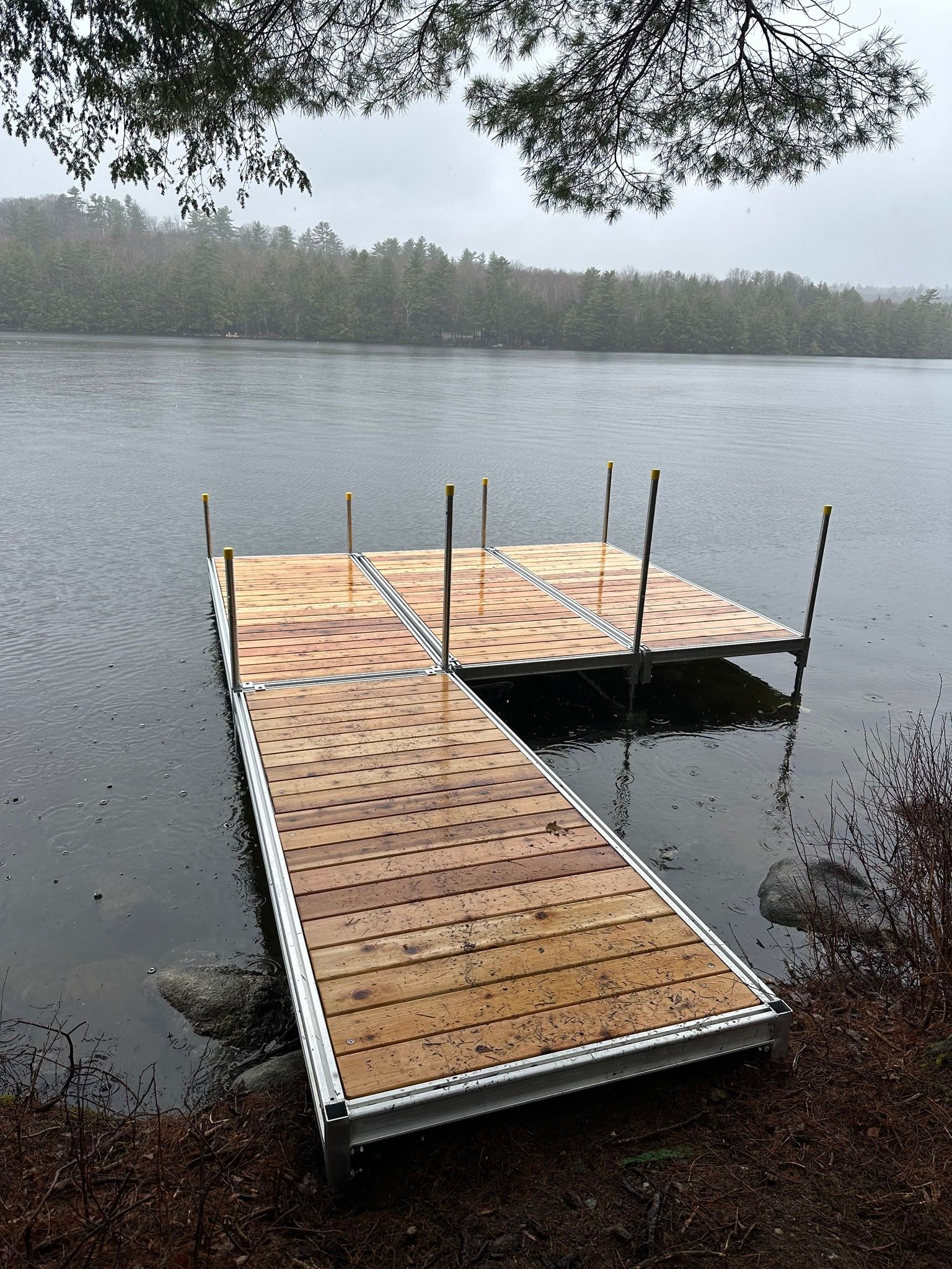 Wooden dock extending into a calm lake under an overcast sky