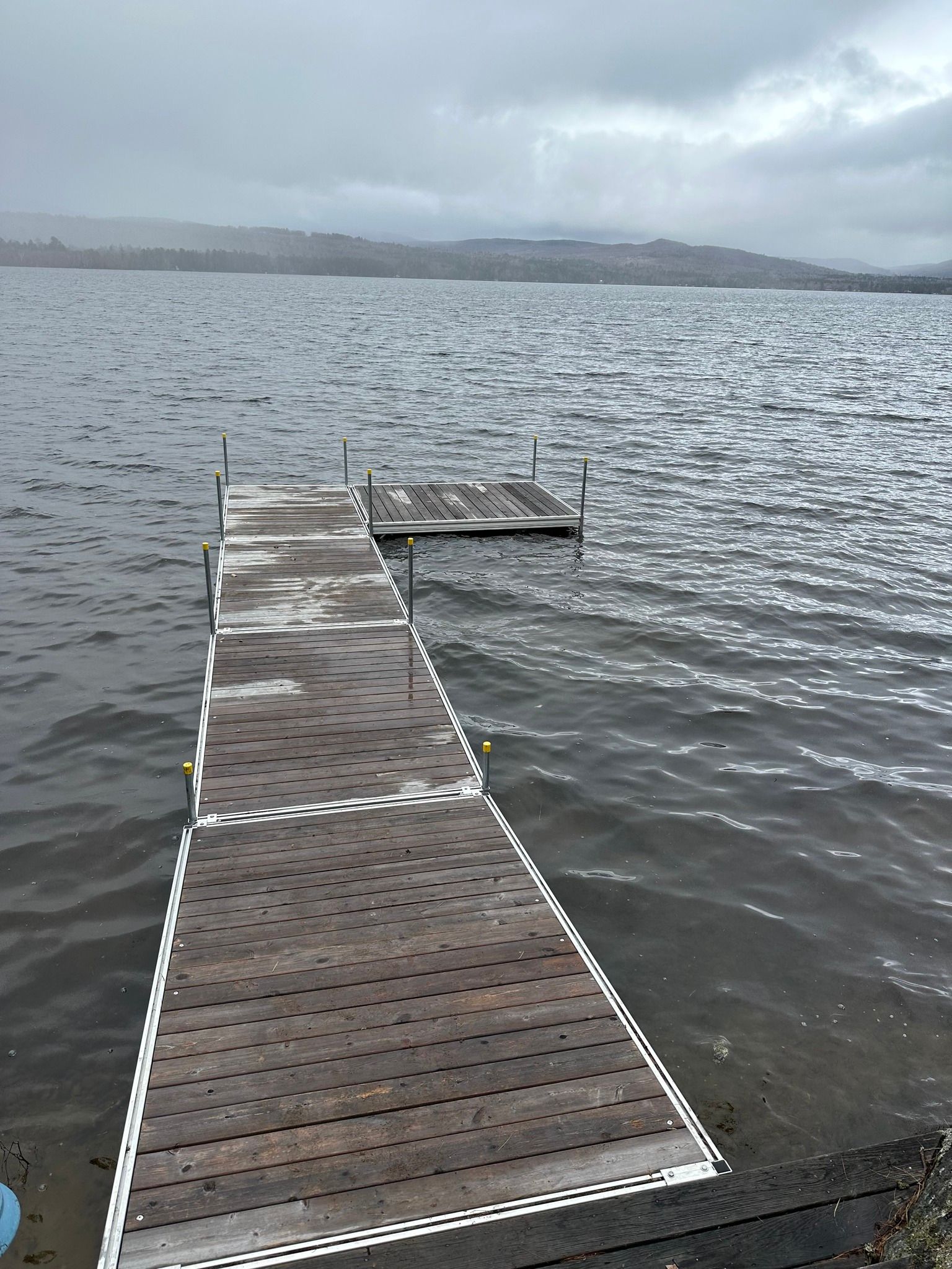 Wooden dock extending into a calm lake under an overcast sky