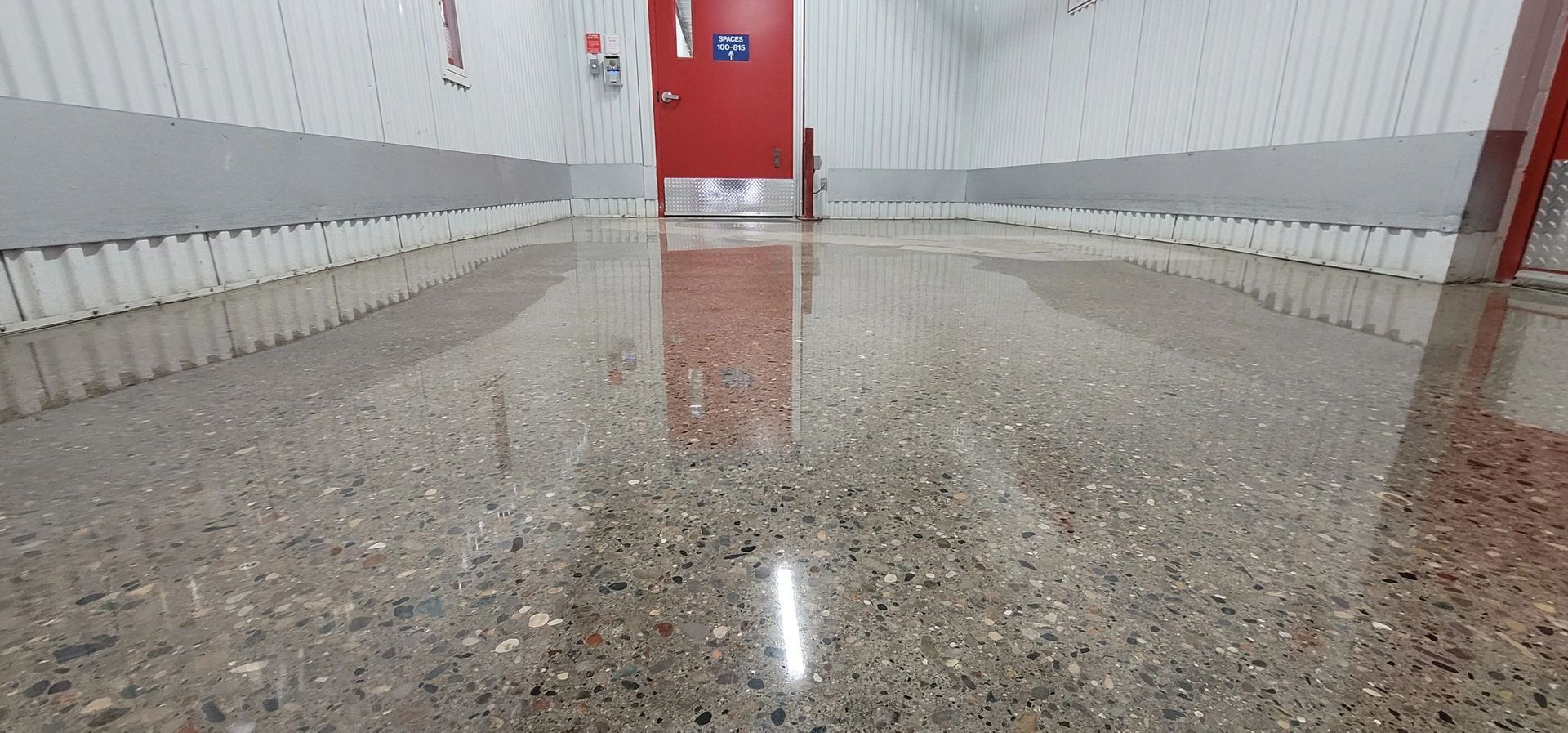 Polished concrete floor reflecting a red door and white walls.