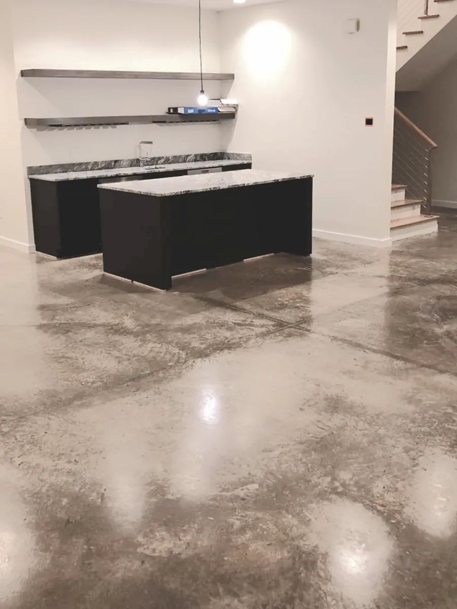 Kitchen with dark cabinets, stainless steel shelves, and polished concrete floor.