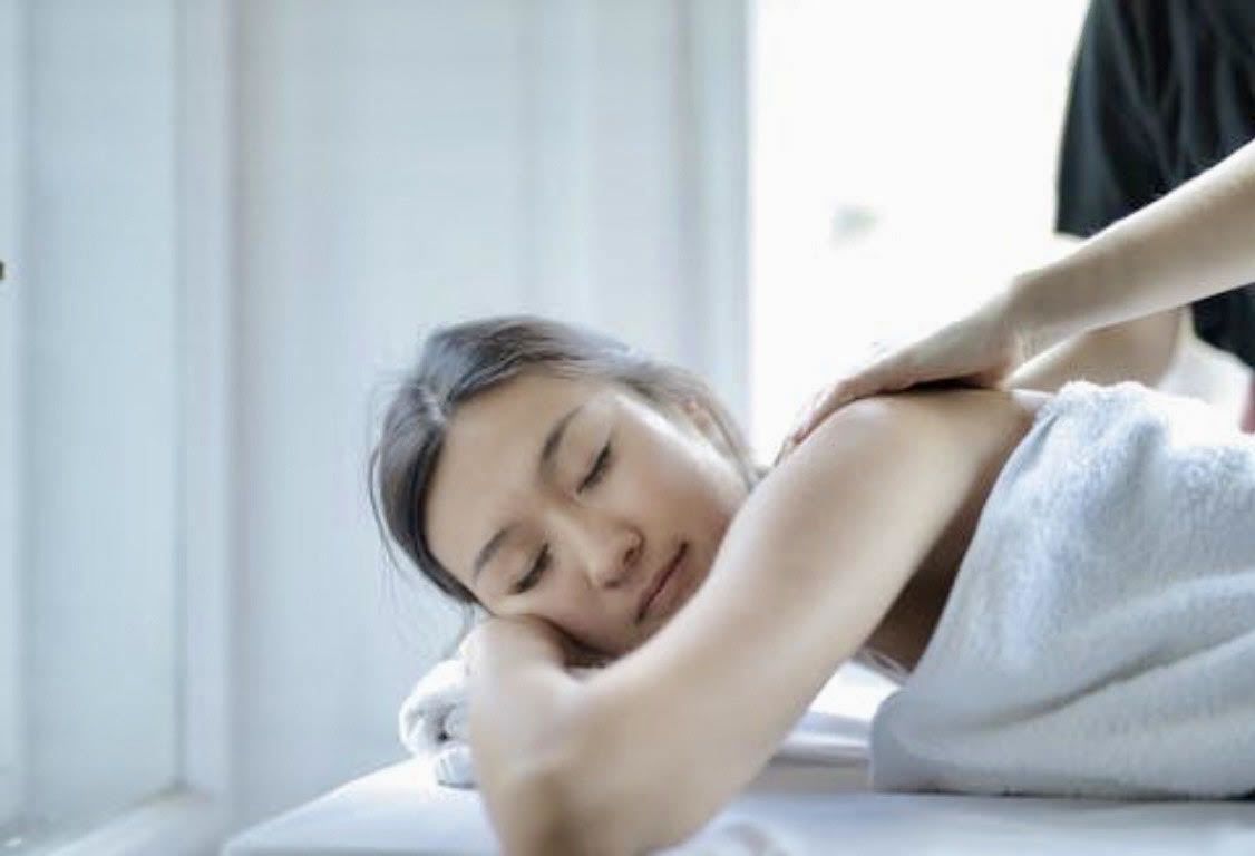 A woman is laying on a table getting a massage.