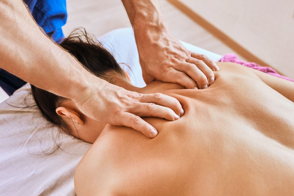 A man is giving a woman a deep tissue massage on her back.