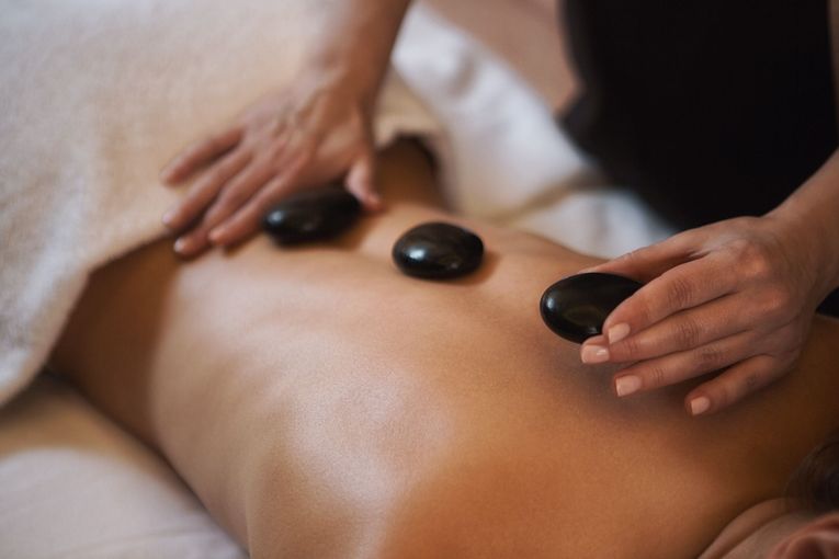 A woman is getting a massage with hot rocks on her back.