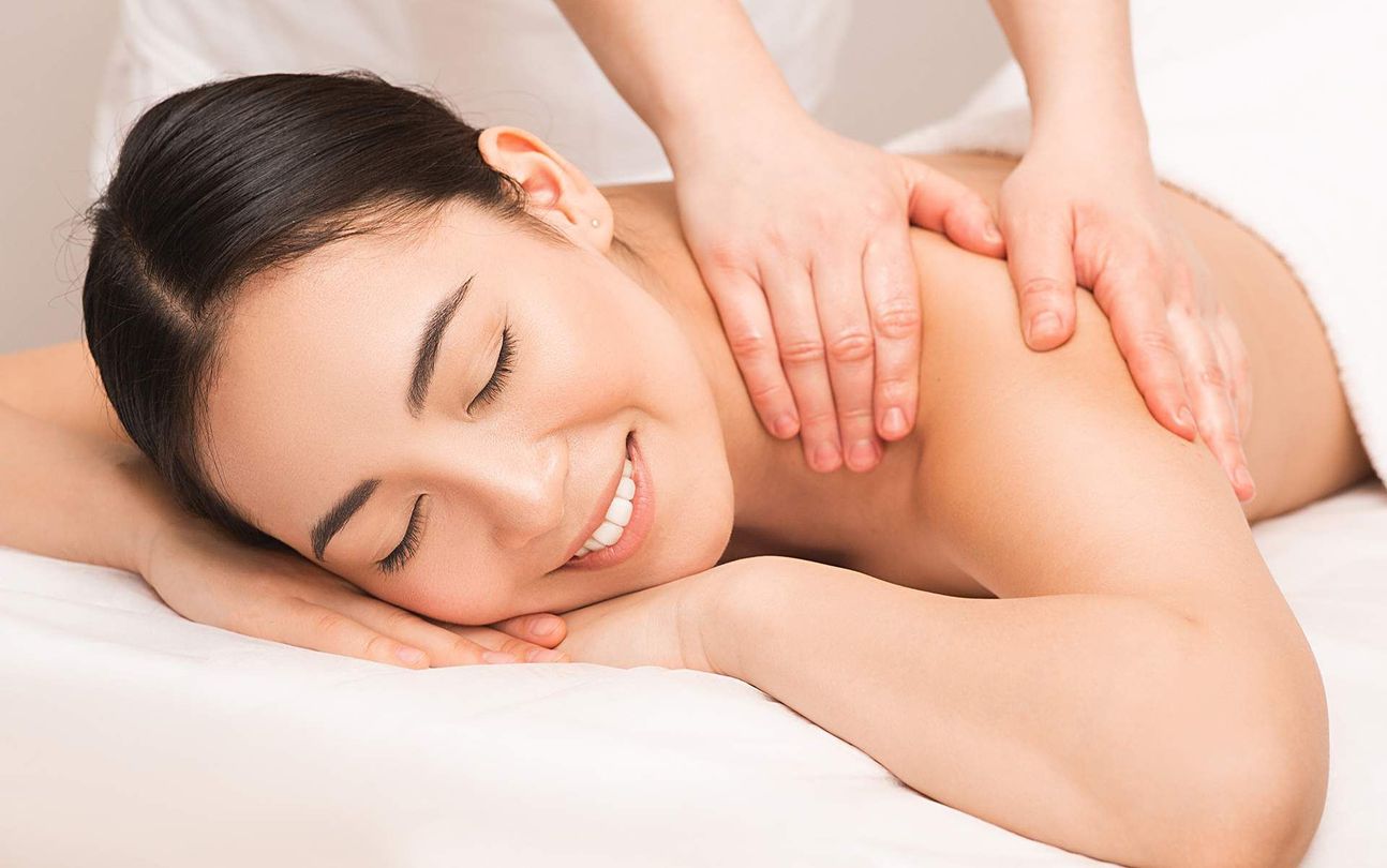 A woman is laying on a bed getting a massage.