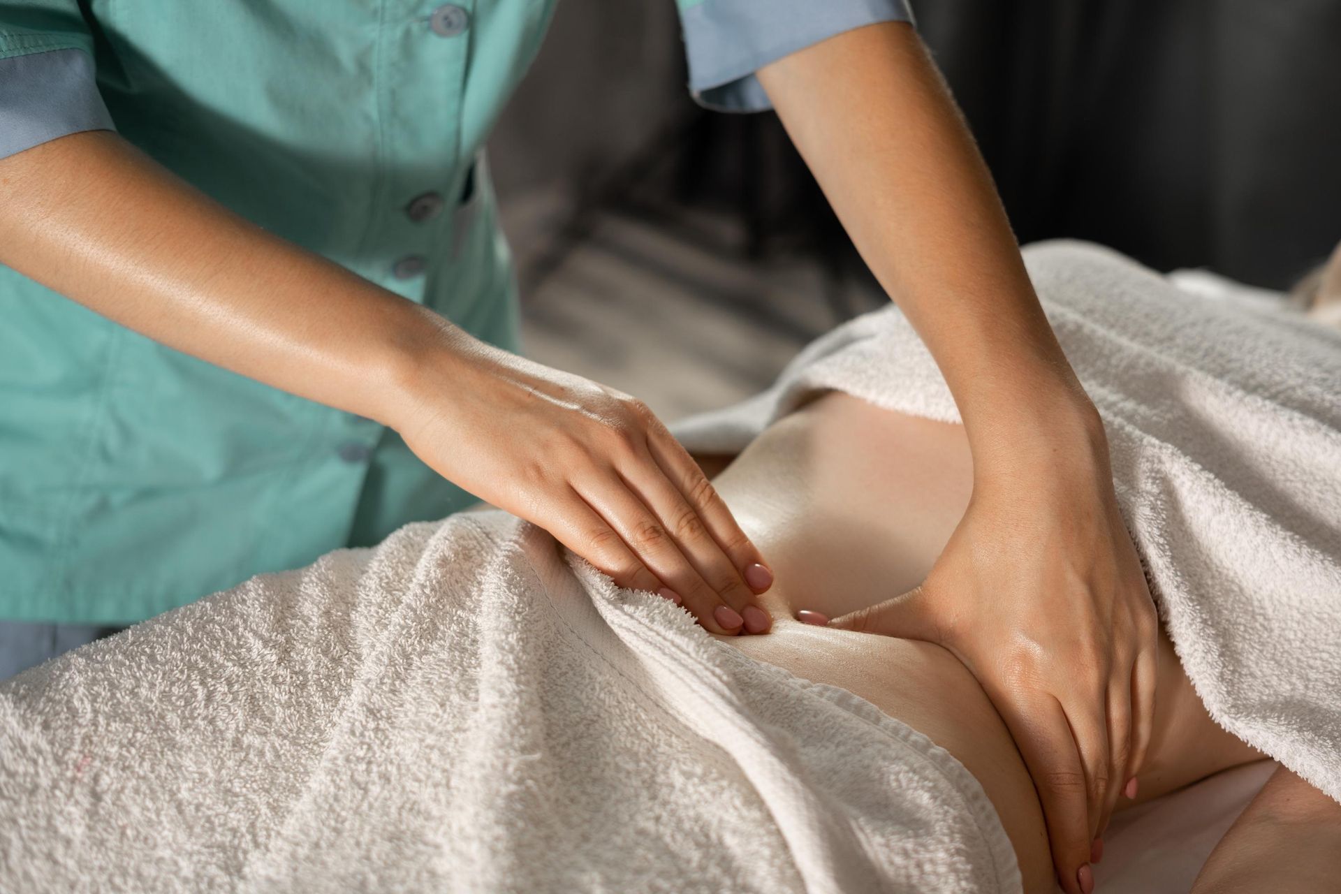 Massage therapist pressing lower back through towel on spa table