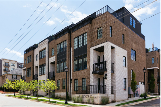 A large brick building with a lot of windows is on the corner of a street.