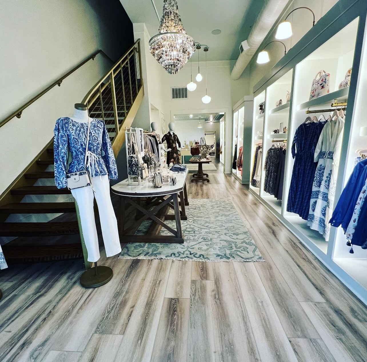 A clothes store with a staircase leading up to the second floor