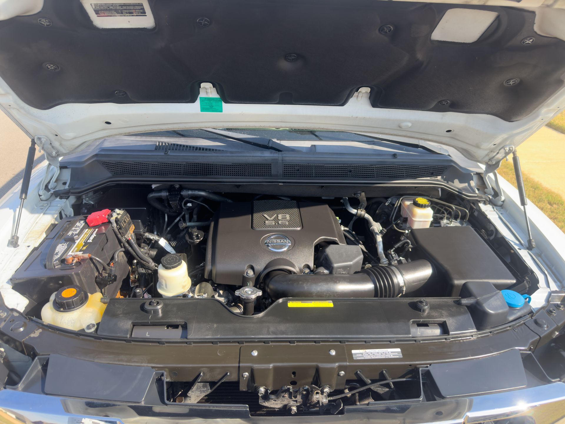 Open car hood showing a clean engine bay with black plastic covers and yellow fluid caps