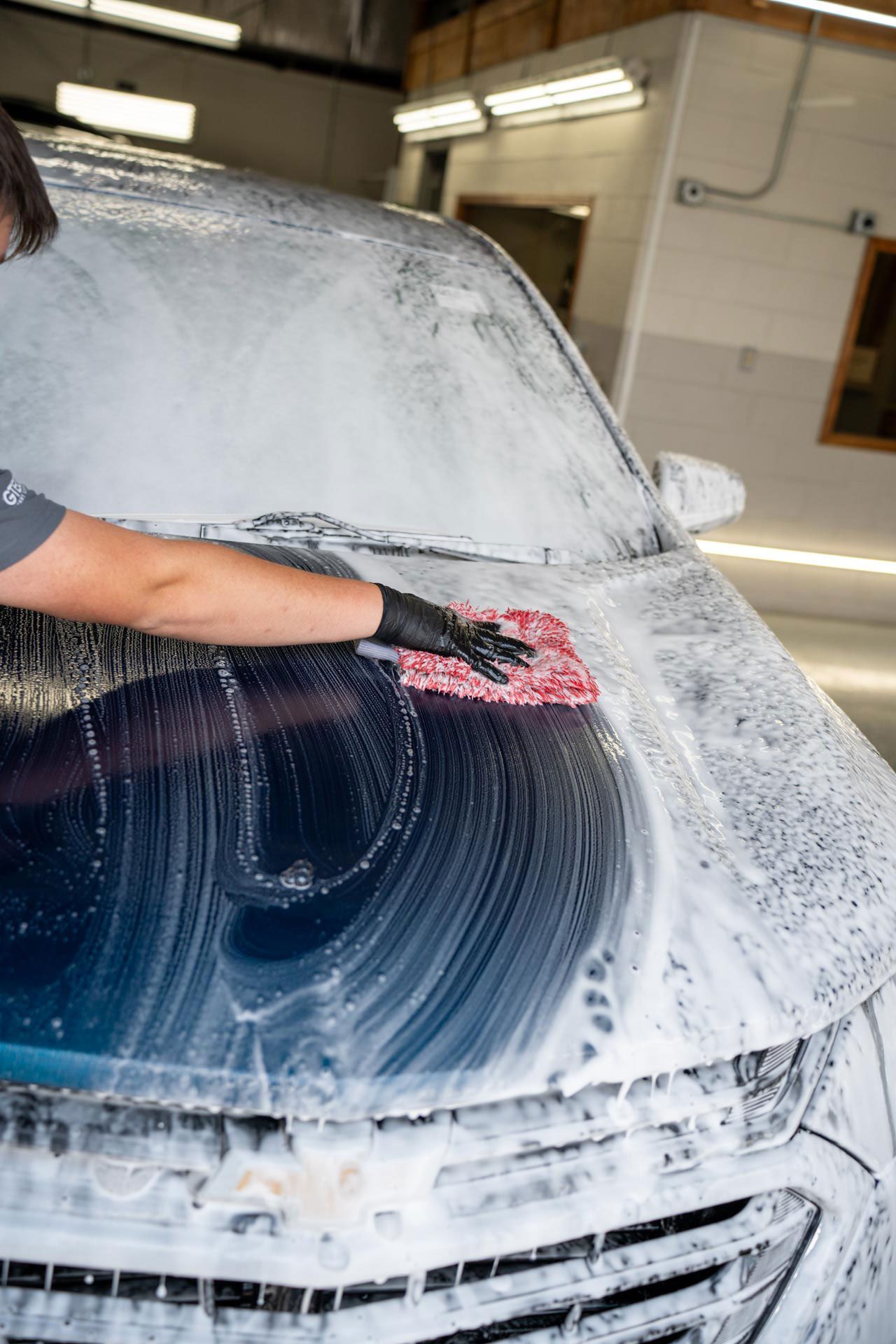 A person is cleaning a car with a towel and spray bottle.