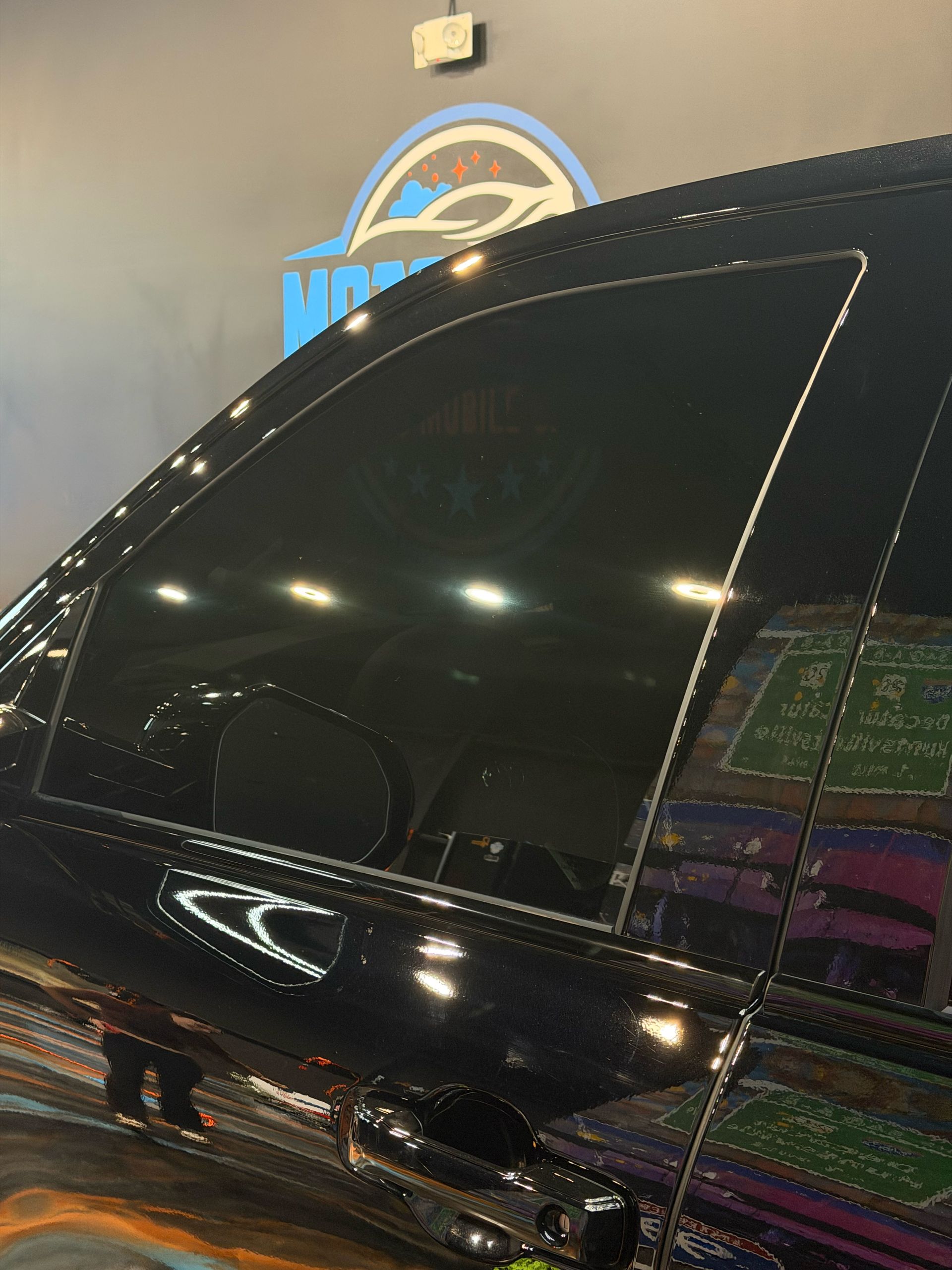 Black SUV with tinted windows parked indoors under bright lights.